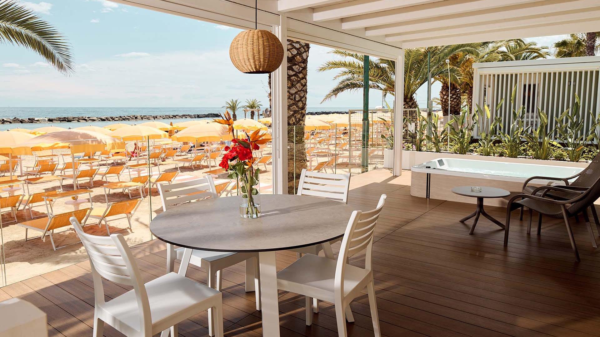 Seaside terrace with chairs, table, and yellow umbrellas.