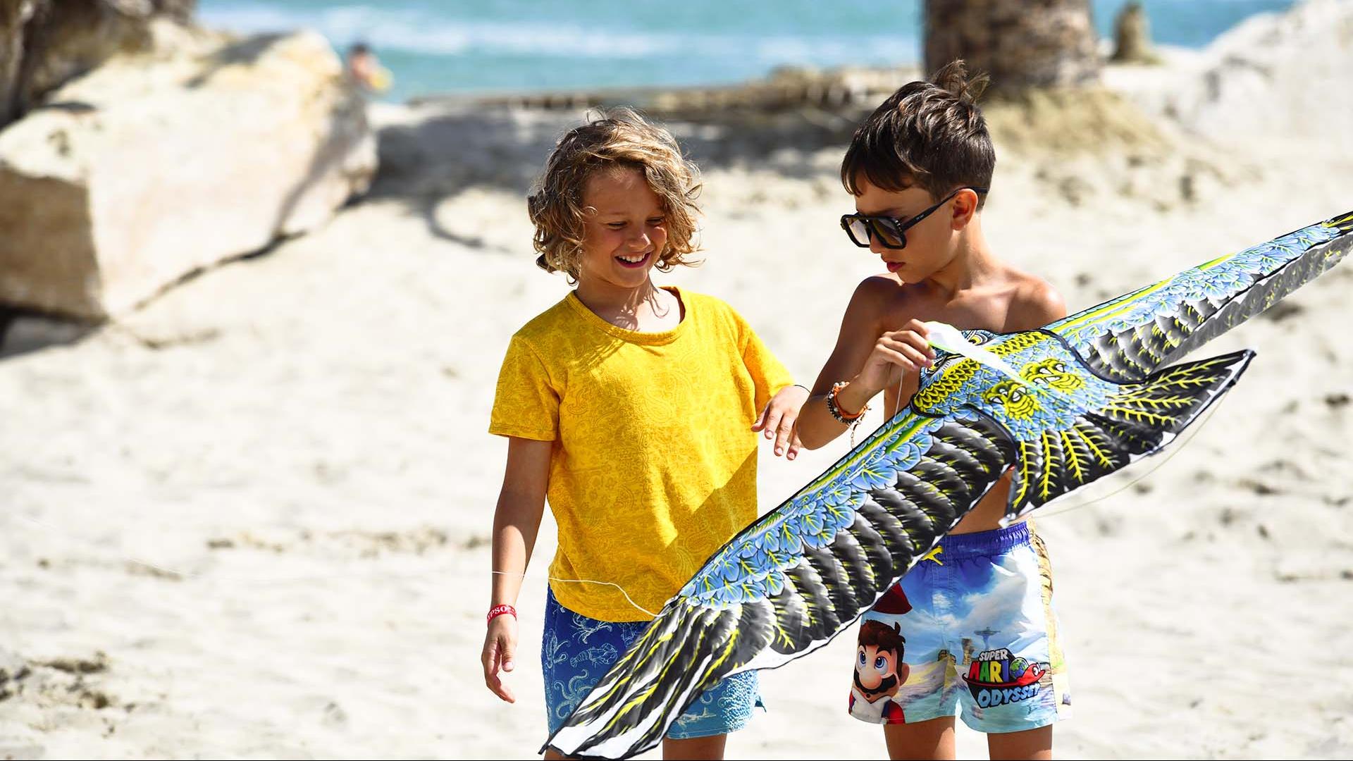 Bambini giocano sulla spiaggia con un aquilone colorato.