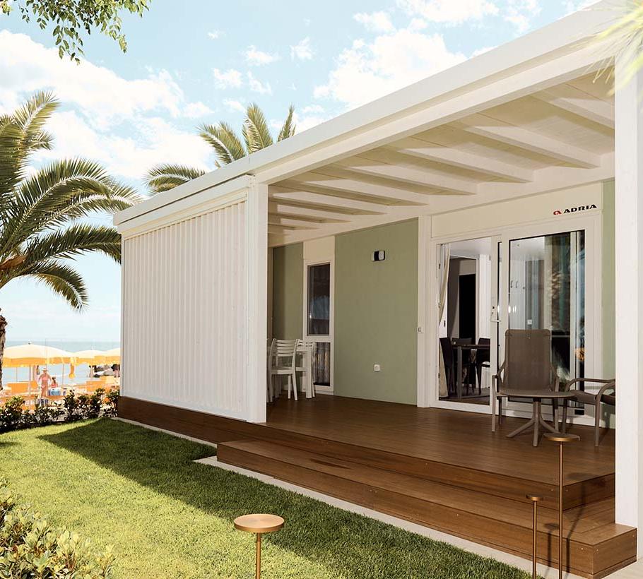 Moderne strandhuis met veranda, palmbomen en gele parasols.